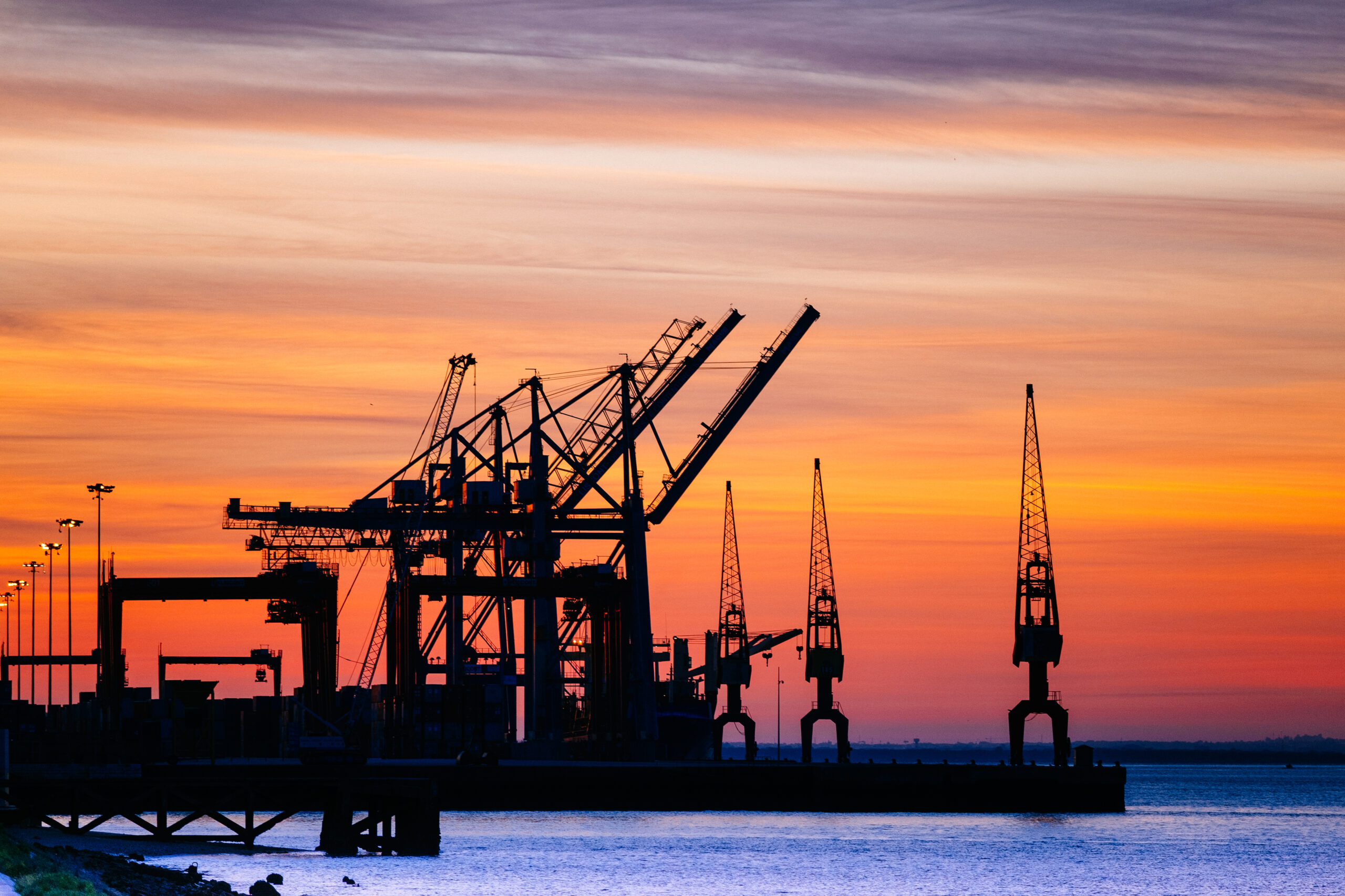 Acidentes fatais na área petroquímica - A beautiful silhouette of port machinery during sunset